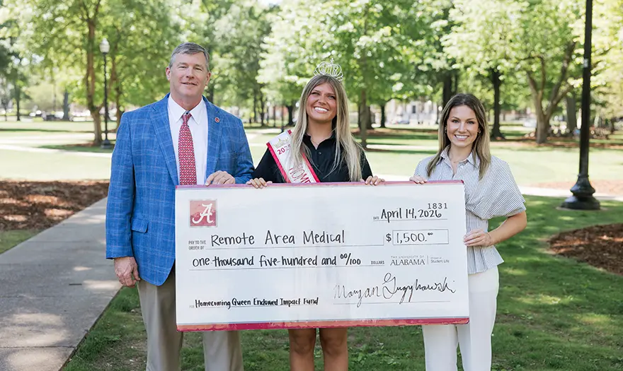 Morgan Grybowski, Dr. Hood and one other person holding a donation check for Remote Area Medical.