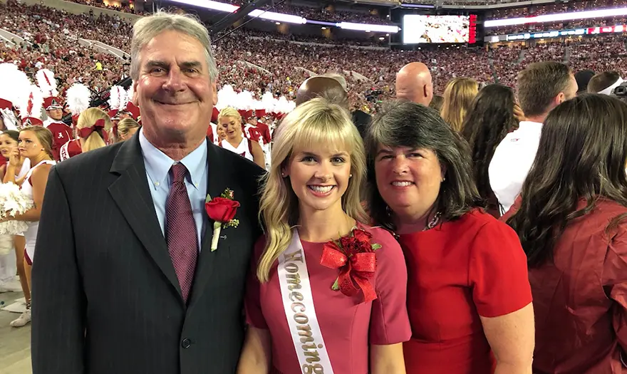 Mike and Cathy Buhai stand with their daughter Katie during a UA Homecoming game.